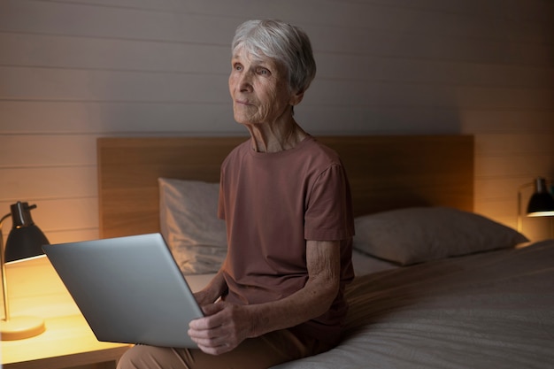 Coup moyen senior woman holding laptop