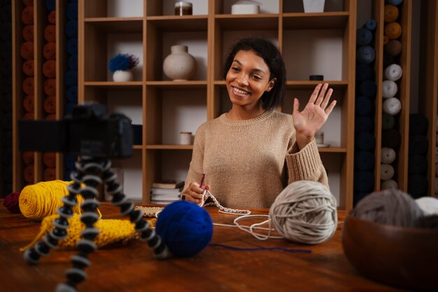 Photo gratuite coup moyen smiley femme tricotant devant la caméra