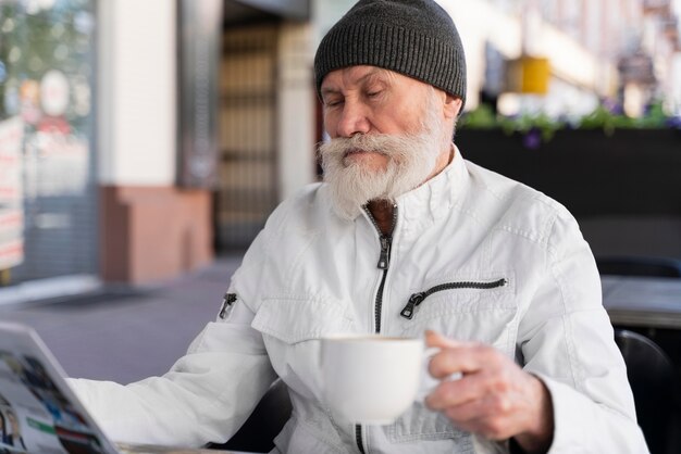 Coup moyen vieil homme tenant une tasse