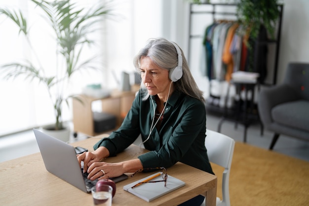 Photo gratuite coup moyen vieille femme avec un casque au bureau