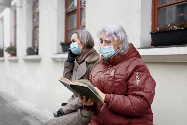 Coup moyen vieille femme lisant à l'extérieur