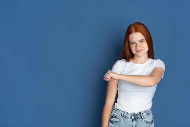 Coup de poing. Portrait de jeune fille caucasienne sur bleu. Beau modèle de femme rousse avec de jolies taches de rousseur.