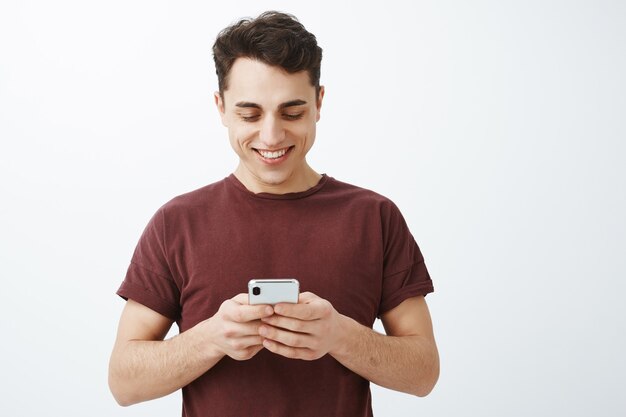 Coup de taille de bel homme sympathique positif en t-shirt rouge avec smartphone