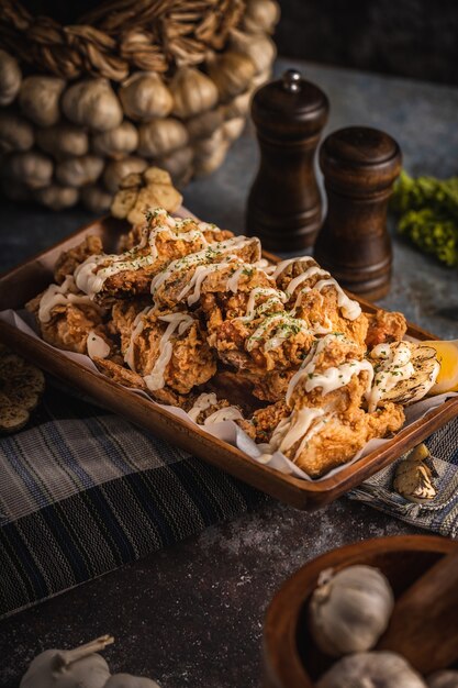 Coup vertical d'ailes de poulet délicieusement cuites avec sauce sur la table sous les lumières