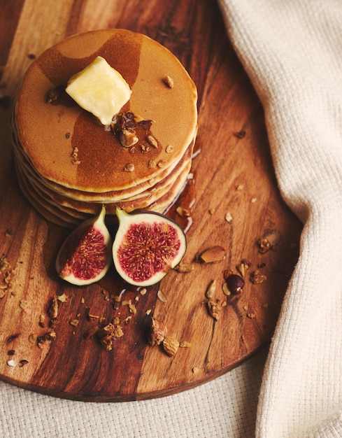 Coup vertical de crêpes au sirop, beurre, figues et noix grillées sur une plaque en bois