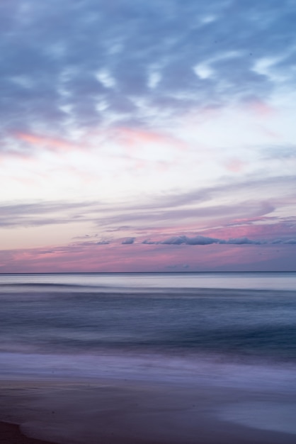 Photo gratuite coup vertical du beau ciel coloré sur la mer pendant le lever du soleil