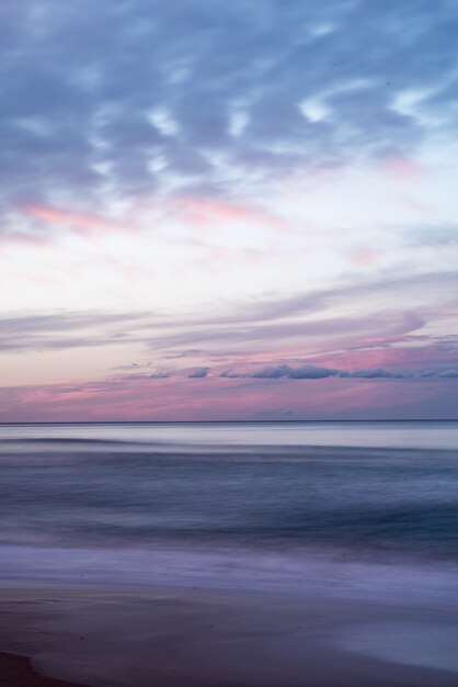 Coup vertical du beau ciel coloré sur la mer pendant le lever du soleil