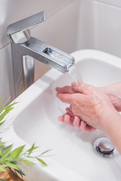 Coup vertical de femme se laver les mains avec du savon et de l'eau