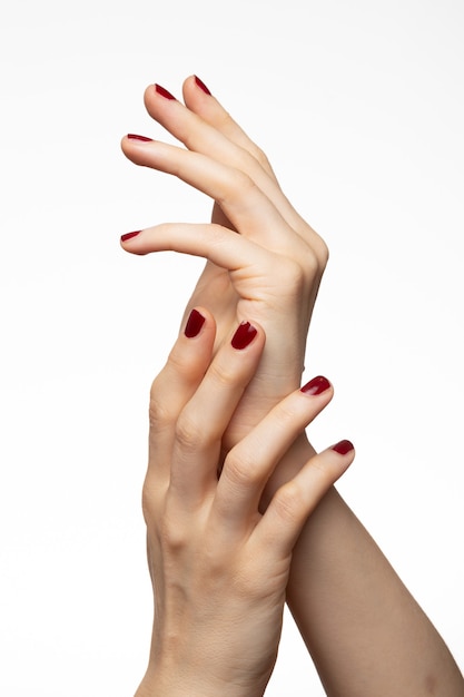 Coup vertical de mains féminines avec vernis à ongles rouge