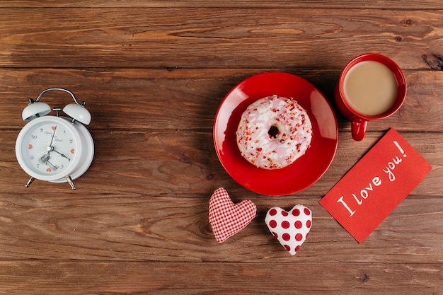 Coupe et beignet sur assiette entre les décorations de la Saint-Valentin