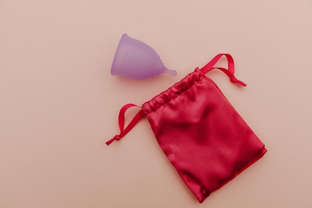 Coupe et sac menstruel violet pastel réutilisable sur fond rose concept d'écologie et de recyclage