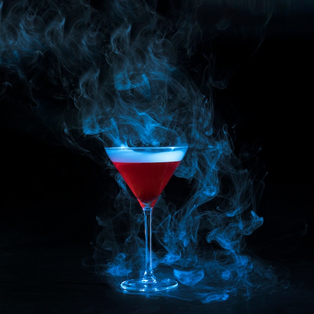 Photo gratuite coupe en verre avec du liquide rouge fumé