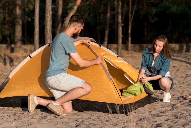 Couple accroupi démontant une tente de camping