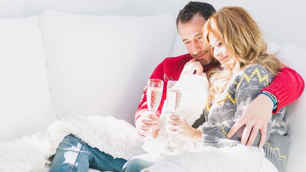 Couple adulte buvant du champagne sur le canapé