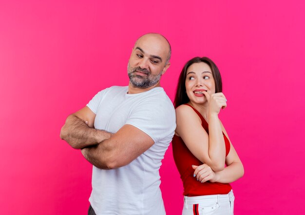 Couple adulte homme confiant debout avec une posture fermée et impressionné femme mordant le doigt à la fois en se regardant