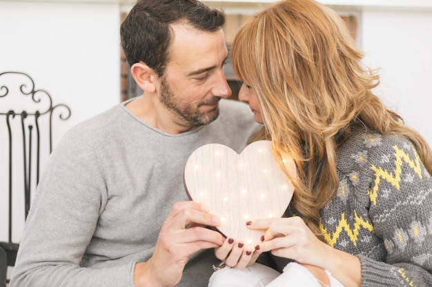 Photo gratuite couple adulte posant avec coeur à la maison