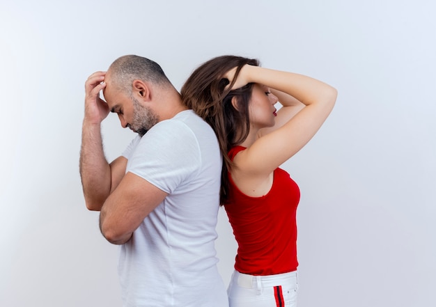 Couple adulte stressé debout dos à dos à la fois en mettant la main sur la tête isolé sur un mur blanc avec copie espace