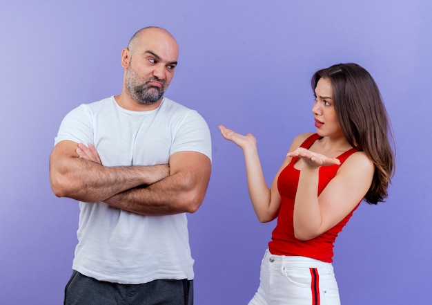 Couple d'adultes en colère se disputant les uns avec les autres homme fronçant les sourcils debout avec une posture fermée et femme mécontente montrant les mains vides