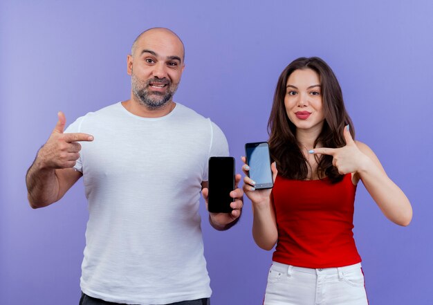 Couple d'adultes confiants montrant les téléphones mobiles et pointant sur eux