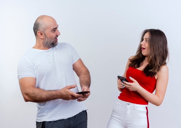 Couple d'adultes impressionné à la fois tenant des téléphones mobiles et se regardant