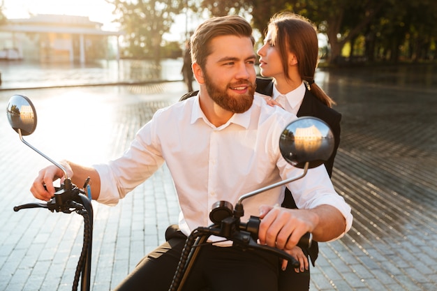 Couple d'affaires insouciant monte sur une moto moderne dans le parc