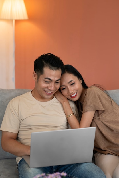 Couple affectueux à la maison travaillant sur un ordinateur portable assis sur un canapé