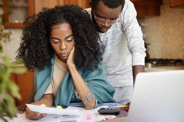 Couple africain stressé ayant de nombreuses dettes essayant de réduire leurs dépenses domestiques pour économiser de l'argent