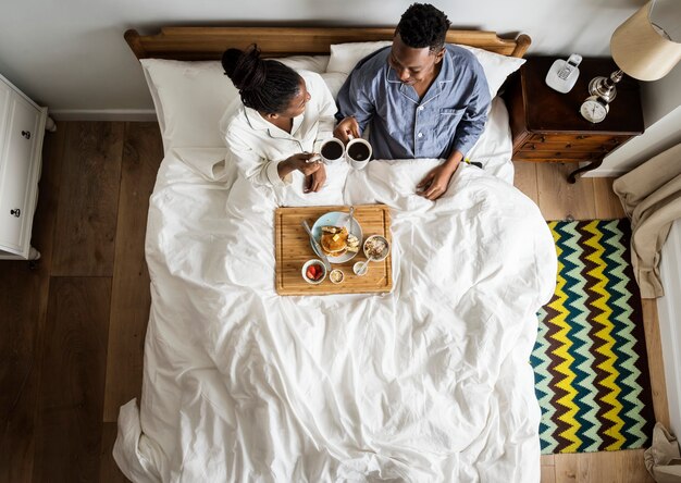 Couple afro-américain au lit prenant son petit déjeuner au lit
