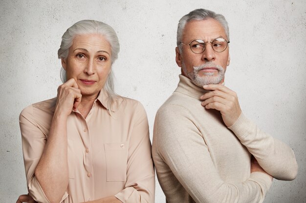 Couple d'âge mûr pose contre le mur de béton blanc