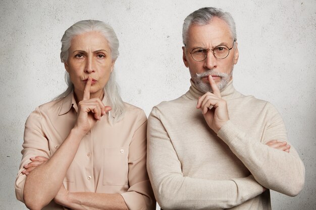 Couple d'âge mûr pose contre le mur de béton blanc