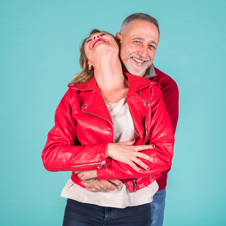 Photo gratuit couple d'âge mûr romantique debout sur fond turquoise