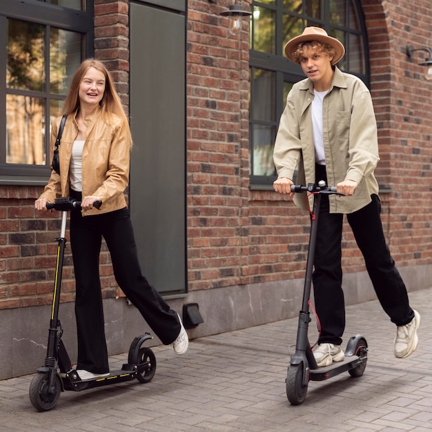 Couple à l'aide de scooters électriques à l'extérieur