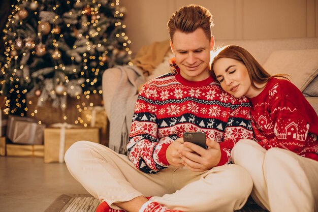 Couple à l'aide de téléphone ensemble à Noël