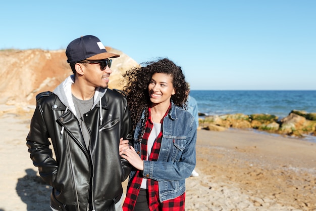 Couple d'amoureux africains marchant à l'extérieur sur la plage