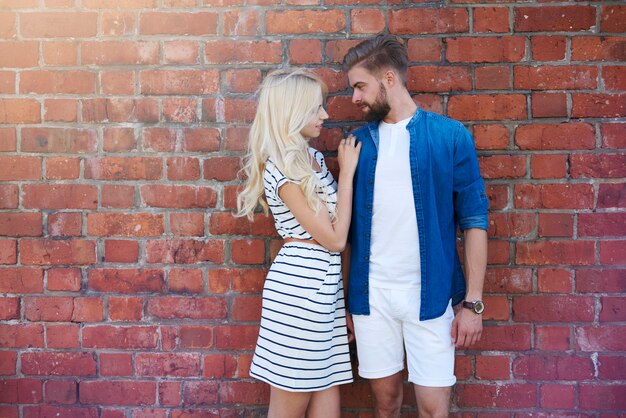 Couple d'amoureux debout devant le mur de briques