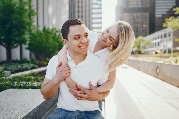 couple d&#39;amoureux jeunes et élégantes en t-shirts blancs et jeans bleu assis dans une grande ville