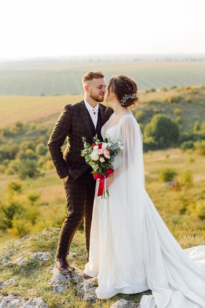 Couple d'amoureux mariés à l'extérieur au coucher du soleil dans une belle journée d'été