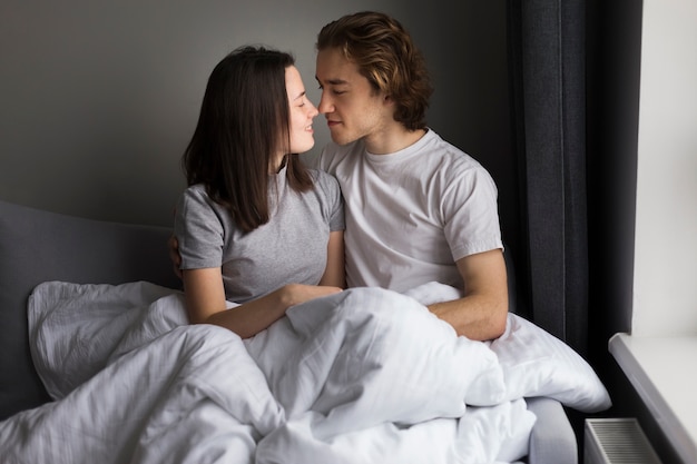 Photo gratuite couple d'amoureux posant dans son lit