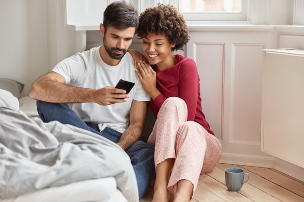 Couple amoureux regarder une vidéo intéressante sur un téléphone portable