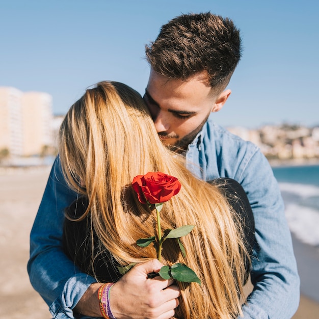Couple d&#39;amoureux avec rose embrassant sur la plage