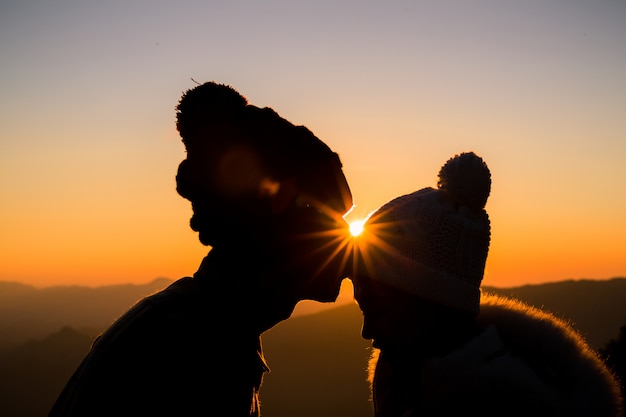 couple amoureux silhouette rétro-éclairage sur la colline au moment du coucher du soleil