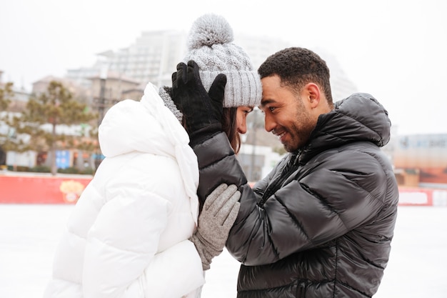 Couple d'amoureux souriant patiner à la patinoire à l'extérieur.