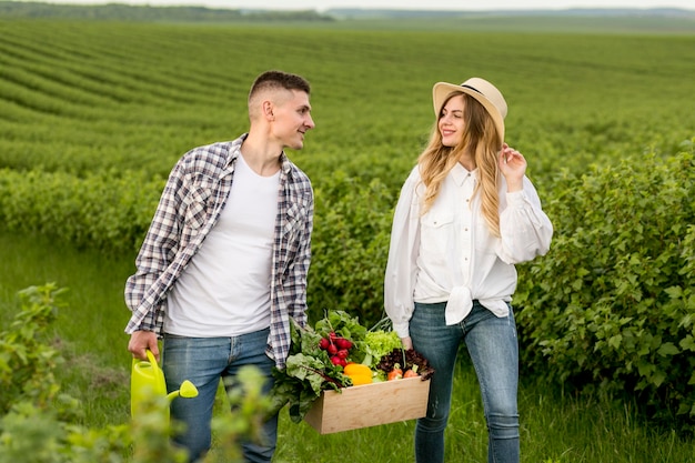 Couple d'angle élevé portant un panier de légumes