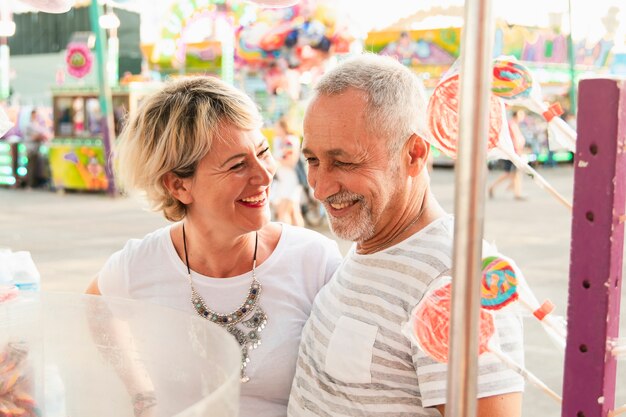 Couple d'angle élevé souriant dans le parc d'attractions