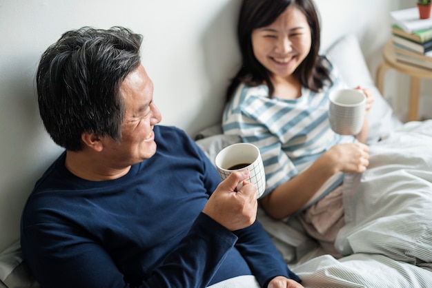 Couple asiatique, boire du café au lit