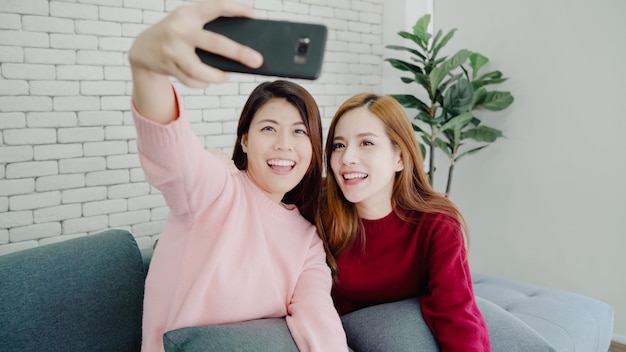Couple asiatique lesbienne, à l&#39;aide de smartphone selfie dans le salon à la maison