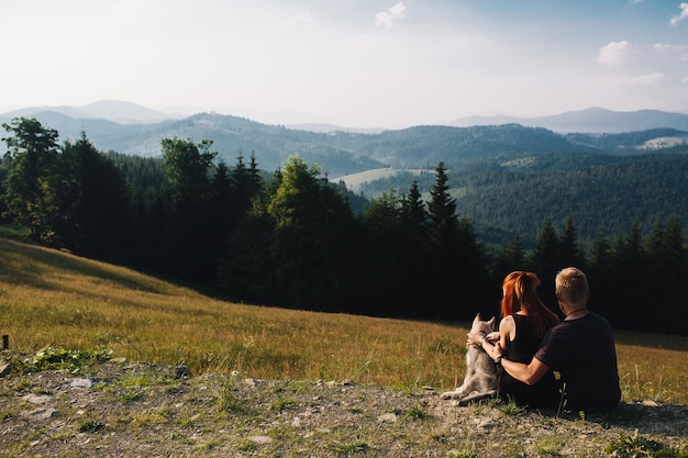 Photo gratuite couple assis sur un champ vert regardant la nature