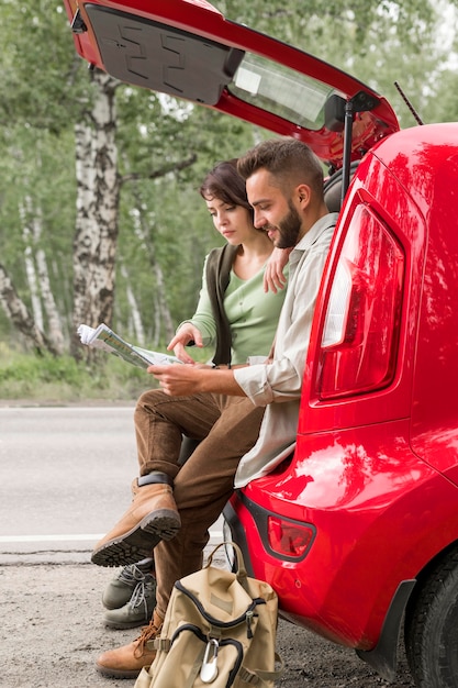 Couple assis dans le coffre à la recherche sur la carte