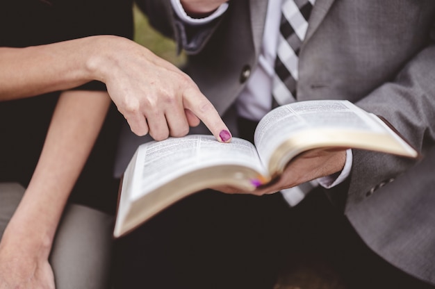 Couple assis dans un jardin et lire un livre ensemble