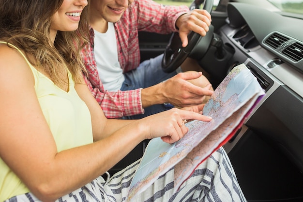 Couple assis dans la voiture en pointant le doigt sur la carte de navigation de l&#39;emplacement